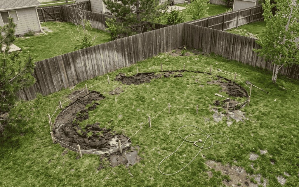 Backyard lawn outlined with string and stakes for a new garden bed after sod removal